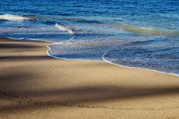 Waves lapping on Waikiki beach with overlapping shadows