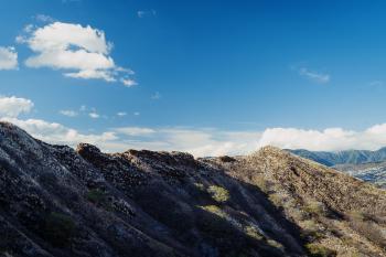 The rim of Diamond Head crater, partly in shadow, with light clouds above