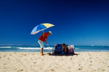 A man planting a parasol in the sand on Waikiki beach