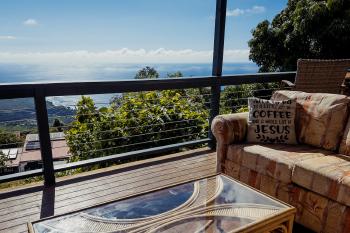 View from a very Christian cafe, the Pacific Ocean in the background and a pillow saying "All I need is a little bit of coffee and a whole lot of Jesus"