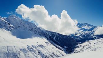Clouds over an expansive landscape of valleys and mountains