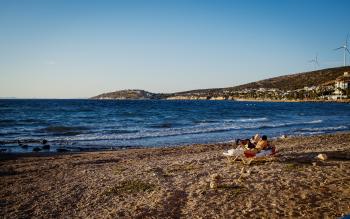 A couple of sunbathers on a rocky beach, sunset