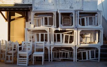 Stacked wooden chairs and tables in front of a wall