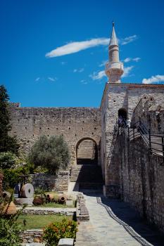 Walls and courtyard of a castle, a minaret in the background
