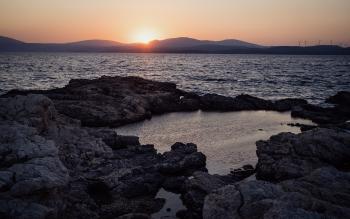 Sunset, the sea and a rock pool in the foreground