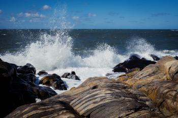 Waves breaking over softly rounded rocks